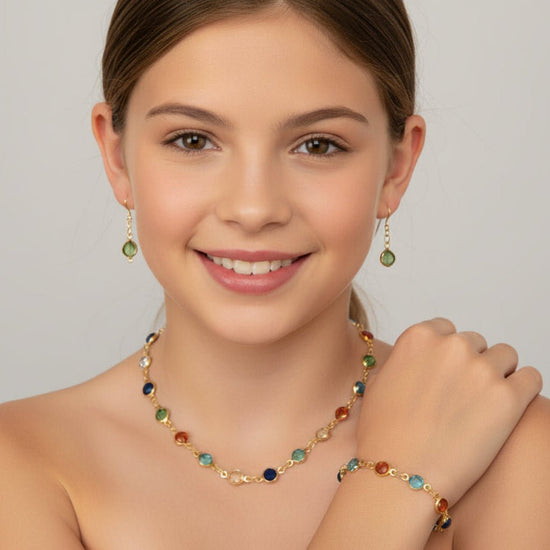Young woman wearing a colorful necklace, earrings, and bracelet against a plain background